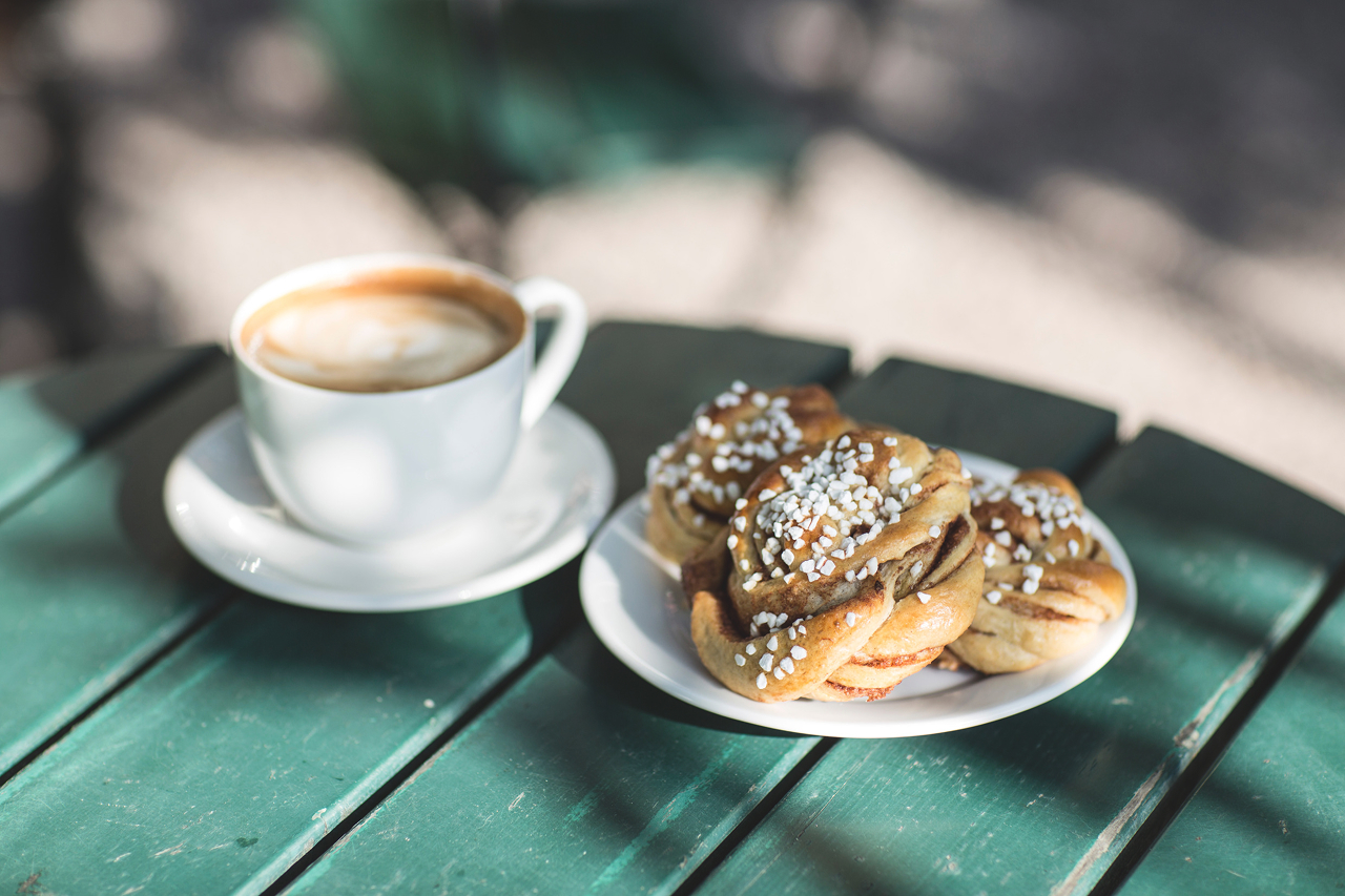 cinnamon bun and coffee with milk on a green table